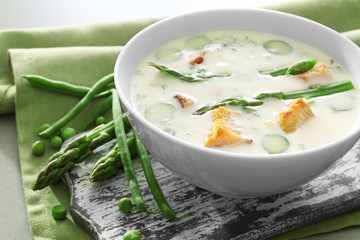 Tasty asparagus soup with crackers on table