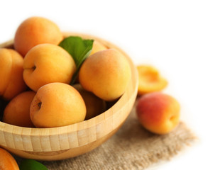 Heap of apricots in wooden bowl on table