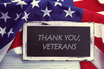 Blackboard with text THANK YOU, VETERANS on USA national flag