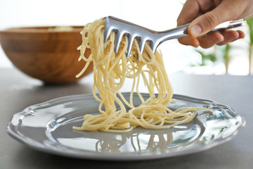 Female hand putting spaghetti onto plate