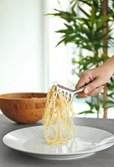Female hand putting spaghetti onto plate