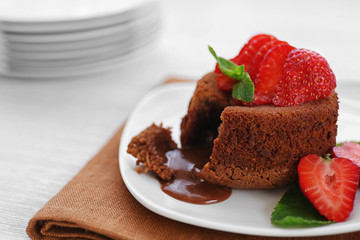 Tasty chocolate fondant with strawberries on white plate, closeup