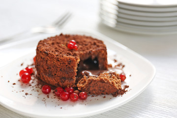Tasty chocolate fondant with red currant on white plate, closeup