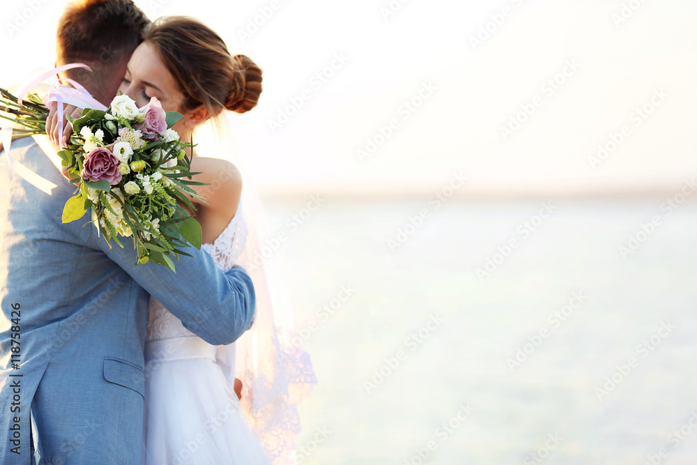 Poster groom and bride hugging, outdoor