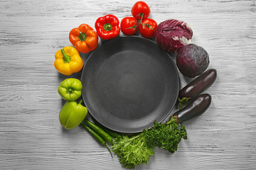Set of vegetables around plate on wooden background