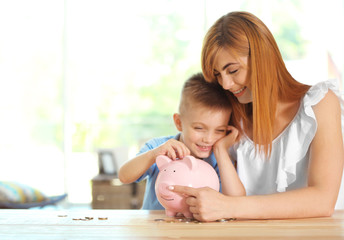 Savings concept. Mother and little boy putting coins into piggy bank