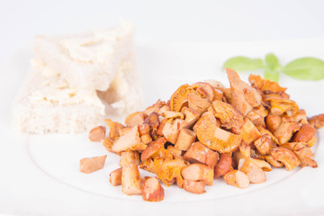 Sauteed chanterelle with garlic and some white bread on a plate decorated with basil