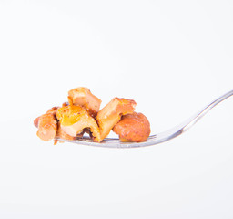 Sauteed chanterelle with garlic on a fork on white background