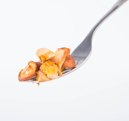 Sauteed chanterelle with garlic on a fork on white background