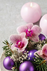 Woman making christmas decorations with violet balls, fir and or