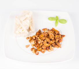 Sauteed chanterelle with garlic and some white bread on a plate decorated with basil