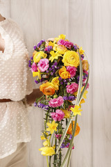 Woman holding wedding bouquet with ranunculus, daffodil and carn