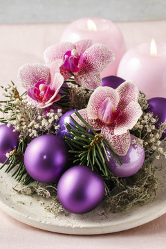 Woman making christmas decorations with violet balls, fir and or