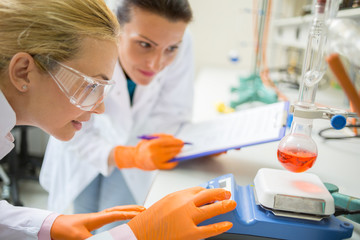 Female assistants adjust device for measuring liquid