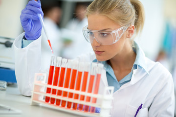 Attractive female chemical assistant work with test tubes