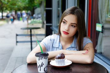 Thoughtful beautiful  young woman in outdoor cafe with coffee an