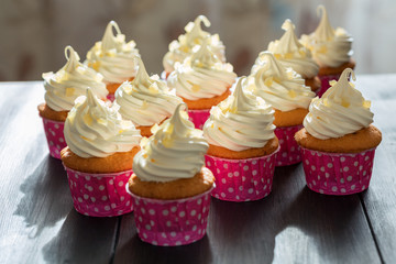 Cupcakes on a wooden table by the window with the five o'clock l