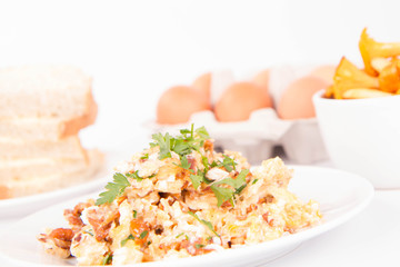 Scrambled eggs with chanterelle and parsley on a white background