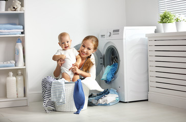mother a housewife with a baby  fold clothes into the washing ma
