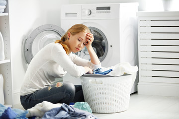 tired unhappy woman housewife  fold clothes into the washing mac
