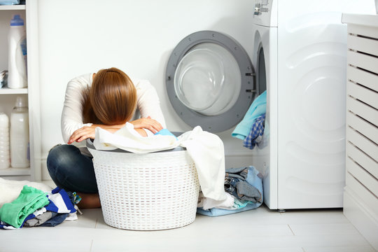 tired unhappy woman housewife  fold clothes into the washing mac
