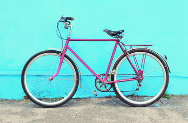 Fototapeta na wymiar Retro pink bicycle stands over colorful blue background