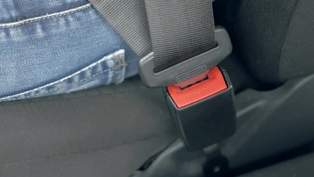 Close up of male hand fastening car safety seat belt while sitting inside of vehicle before driving. Safe travel is one of great importance on the road