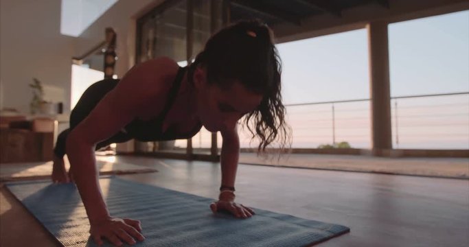 Fitness young woman doing push ups on exercise mat. Healthy young female working out at home.
