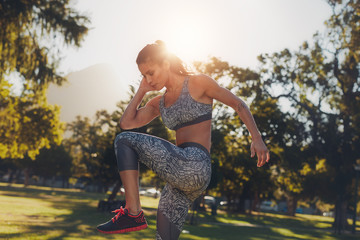 Young woman doing stretching workout at a park.