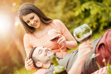Obraz premium Cute young couple drinking red wine in park