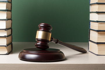 Law concept - Book with wooden judges gavel on table in a courtroom or enforcement office.