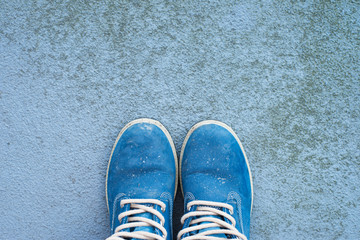 blue colour, dirty hiking boots on a concrete, rough background with lots of copy space, top view, horizontal