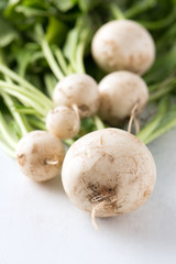 bundle of freshly harvested, dirty, organic farm grown, white turnips over white background, close up