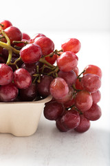 bunch of ripe, organic, seedless purple grapes in a container, isolated over white board, close up, vertical