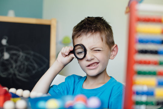 Back to school. Portrait of a school boy looking through a magnifying glass.