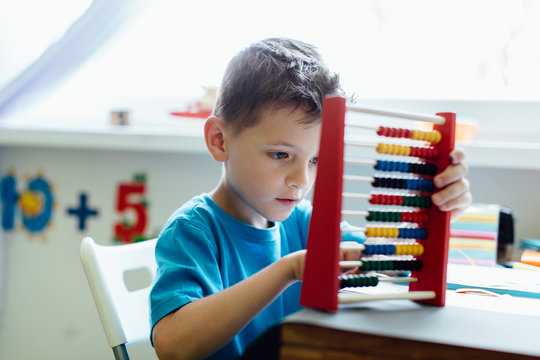 Studying at home. Portrait of a thinking school boy learning maths with an abacus.