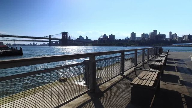 A daytime morning establishing shot of Brooklyn skyline and Bridge as seen from Pier 15 East River Esplanade.  	