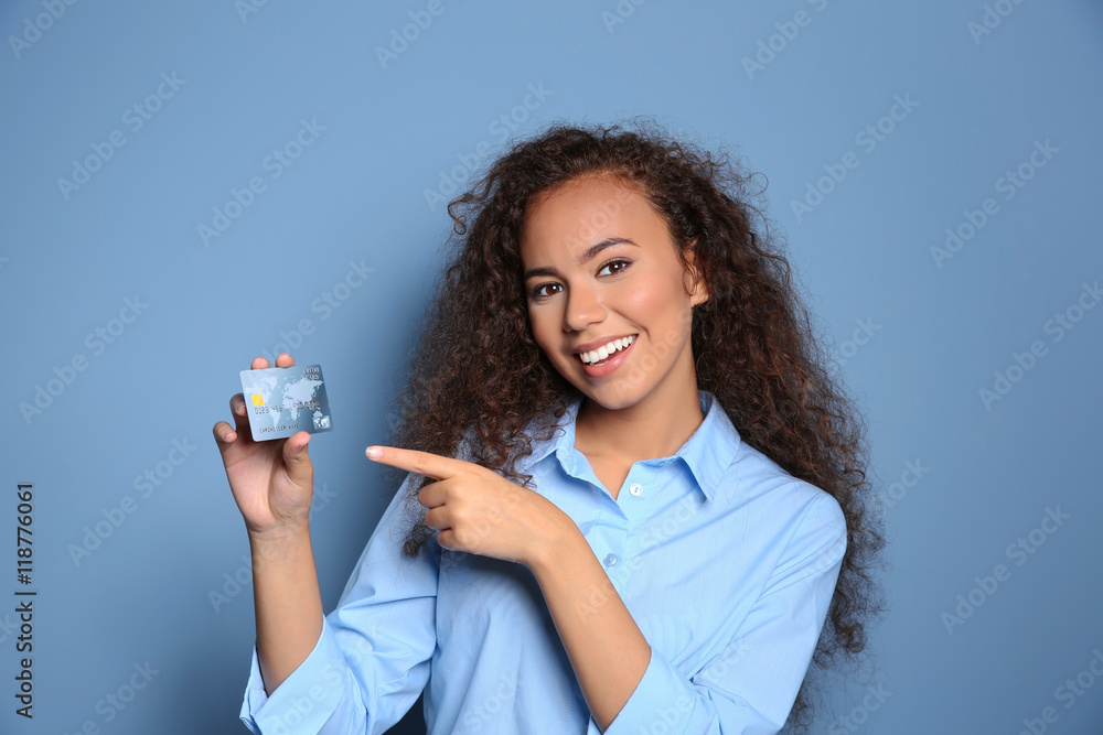 Wall mural attractive woman holding credit card on blue background