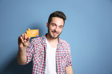 Young man holding credit card on blue background