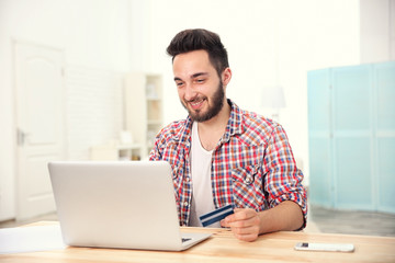 Man using credit card and laptop for online shopping