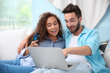 Young man and woman using credit card and laptop for online shopping