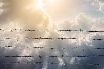 Barbed wire fence with cloudy sky and ray light. Feel silent and lonely and want freedom