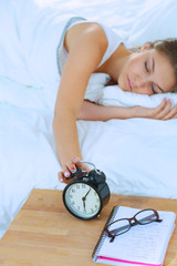 A young woman putting her alarm clock off in the morning