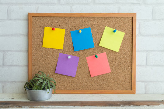 Cork board with color paper note on white background.
