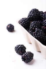 close up of organic blackberries in a farmer's market container, isolated over white board, vertical