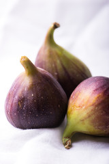 close up of organic, fresh figs grouped and isolated on white kitchen cloth, vertical