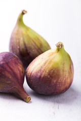 close up of organic, fresh figs grouped and isolated on rustic white wooden board, vertical