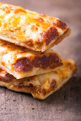 stack of cheese pizza slices, close-up and isolated on brown rustic wooden background