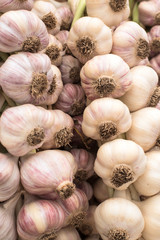 stack of white purple garlic bulbs on display for sale at an outdoor farmers market, nobody, vertical