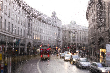 Fototapeta premium zamazany widok ruchu drogowego w Londynie w deszczowy dzień przez okno autobusu. krople deszczu na szybie autobusu